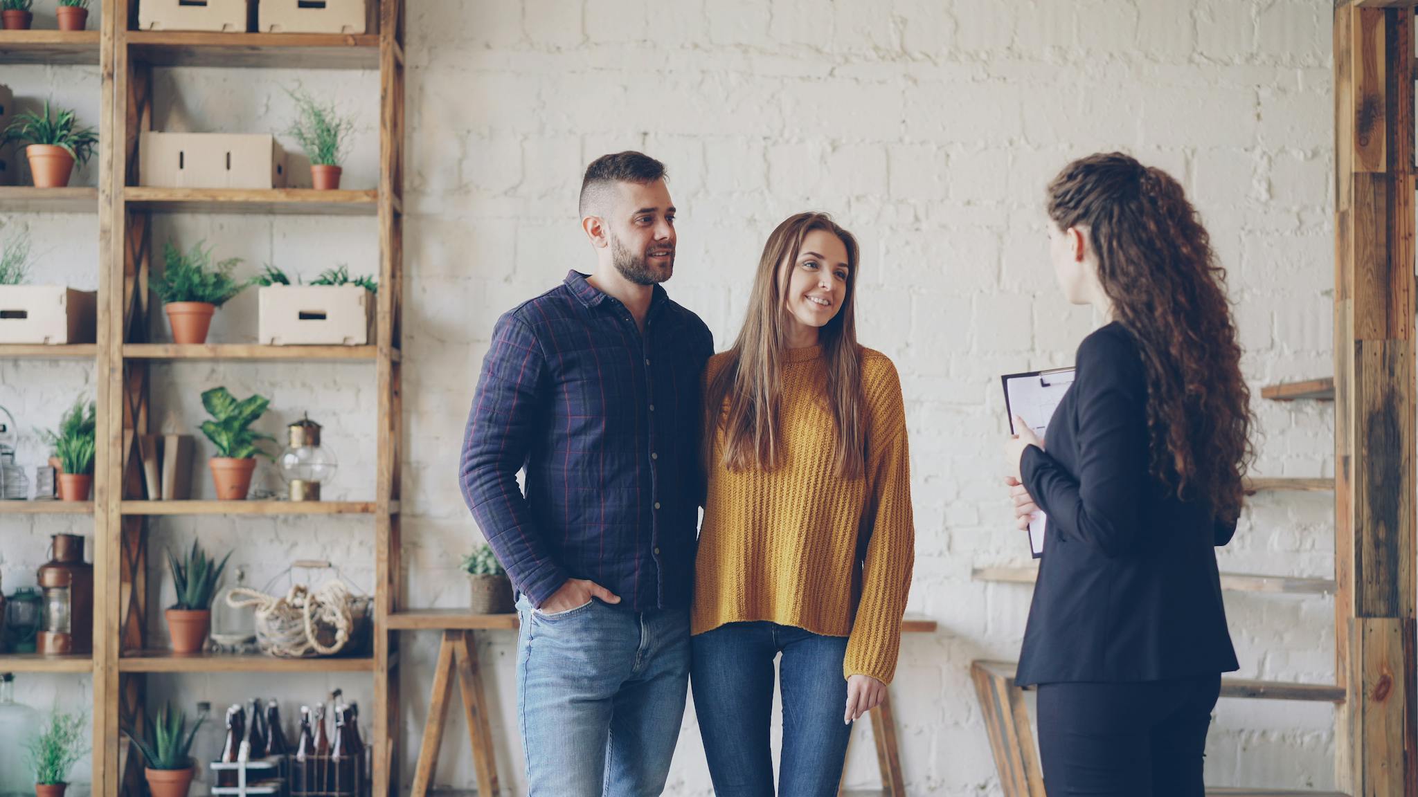 Young couple discussing with a real estate agent in a modern indoor setting.